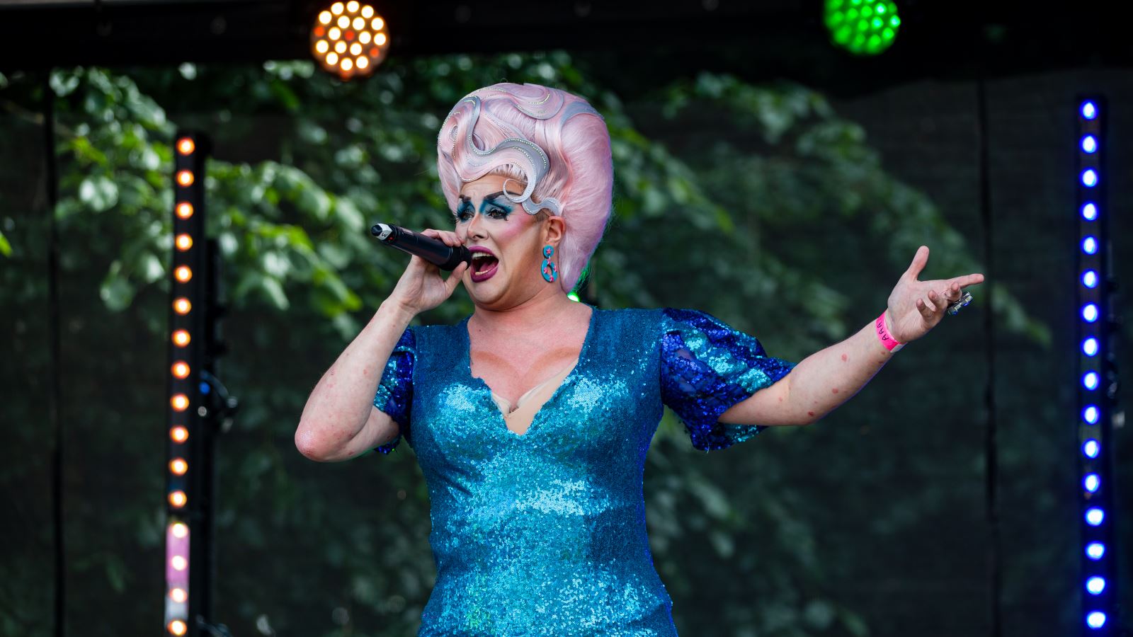 A drag queen in a blue dress on an outdoor stage